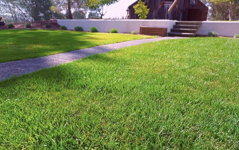 Beautifully illuminated modern home exterior with a lush lawn and wet driveway in Boise, Idaho.